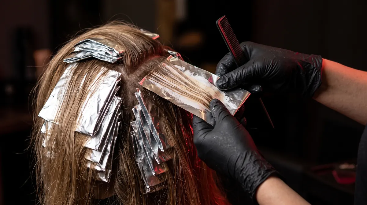 Hände falten Alufolie um eine bemalte Haarpartie, daneben weitere Folien